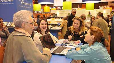 La présidente de Femmes au-delà des mers, Gisèle Bourquin, discute et rit avec d’autres femmes au salon du livre 2012.